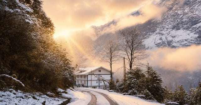 Golden Himalayan sunrise over the snowy road and peaks above Lachung
